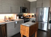 Thumbnail 6 of 17 - A kitchen with a wooden table and stainless steel appliances.