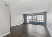 Thumbnail 95 of 151 - A room with a wooden floor and a view of a cityscape through the windows.