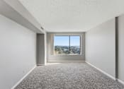 Thumbnail 108 of 151 - A room with a carpeted floor and a window overlooking a cityscape.