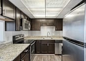 Thumbnail 147 of 151 - A modern kitchen with dark wood cabinets and stainless steel appliances.