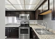 Thumbnail 146 of 151 - A modern kitchen with dark brown cabinets and stainless steel appliances.
