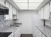 Thumbnail 102 of 151 - A kitchen with white cabinets and a granite countertop.