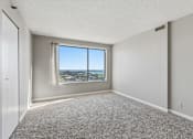 Thumbnail 111 of 151 - A room with a carpeted floor and a window overlooking a cityscape.