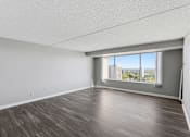 Thumbnail 149 of 151 - A spacious room with wooden flooring and a large window overlooking a cityscape.