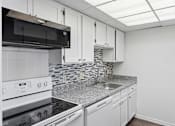 Thumbnail 96 of 151 - A kitchen with white cabinets and a black microwave.