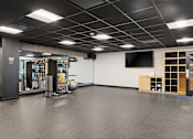Thumbnail 65 of 151 - A gym with a grey floor and a white wall with a television.
