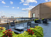 Thumbnail 64 of 151 - A rooftop patio with chairs and tables overlooking a city skyline.
