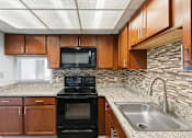 Thumbnail 110 of 151 - A kitchen with a black oven and wooden cabinets.