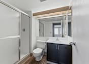 Thumbnail 140 of 151 - A bathroom with a toilet, sink, and mirror.