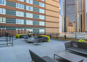 Thumbnail 62 of 151 - A patio with grey furniture and plants in front of a building.