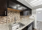 Thumbnail 128 of 151 - A kitchen with a stone backsplash and dark cabinets.