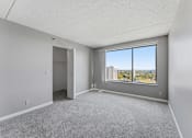 Thumbnail 138 of 151 - A room with a carpeted floor and a large window overlooking a cityscape.