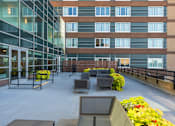 Thumbnail 59 of 151 - A modern building with a glass facade and a balcony with furniture.