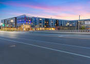 Thumbnail 82 of 82 - a city street with a large blue building at sunset