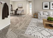 Thumbnail 4 of 26 - A living room with a grey rug and a brown jacket hanging on the wall.