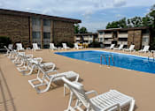 Thumbnail 23 of 29 - A row of white chairs are lined up on a tan pool deck.