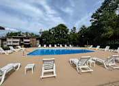 Thumbnail 25 of 29 - A pool surrounded by white chairs and trees.