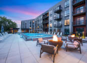 Thumbnail 77 of 82 - an outdoor pool with chairs and a fire pit at dusk