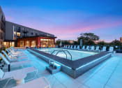 Thumbnail 80 of 82 - a pool with chairs and a building at dusk
