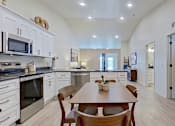 Thumbnail 3 of 12 - A wide angle shot of the kitchen and dining area showcasing vaulted ceilings.