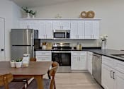 Thumbnail 1 of 12 - Kitchen with white cabinetry, stainless steel appliances, and dark modern countertops