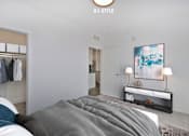 Thumbnail 5 of 46 - A bedroom with a bed, a clothing rack, and a painting on the wall.