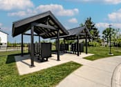 Thumbnail 3 of 59 - A black pavilion with a metal roof is situated in a grassy area.