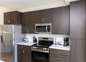 Thumbnail 24 of 46 - A modern kitchen with dark brown cabinets and stainless steel appliances.