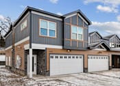 Thumbnail 26 of 26 - A modern house with a grey and brown exterior and a white garage door.