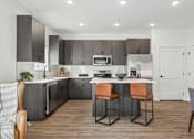 Thumbnail 3 of 26 - A modern kitchen with a center island and bar stools.