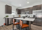 Thumbnail 4 of 26 - A modern kitchen with a white island and stainless steel appliances.