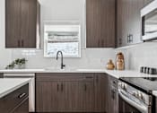 Thumbnail 6 of 26 - A kitchen with brown cabinets and a white countertop.