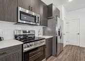 Thumbnail 5 of 26 - A modern kitchen with a stainless steel refrigerator and microwave above the stove.