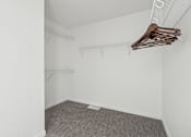 Thumbnail 23 of 26 - A room with a grey carpet and clothes hanging on a rack.