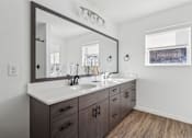 Thumbnail 17 of 26 - A bathroom with a large mirror, a sink, and a window.