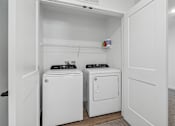 Thumbnail 25 of 26 - A white laundry room with a washer and dryer.