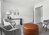 Thumbnail 16 of 26 - A living room with grey chairs and a wooden ottoman.