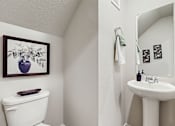 Thumbnail 5 of 12 - A white toilet sits next to a white sink in a small bathroom.