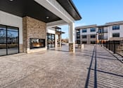 Thumbnail 24 of 27 - A modern building with a stone fireplace and a long concrete patio.