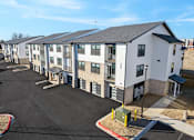 Thumbnail 12 of 27 - A parking lot in front of apartment buildings.