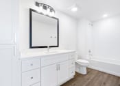 Thumbnail 10 of 27 - A white bathroom with a mirror, sink, toilet, and bathtub.