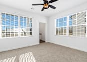Thumbnail 8 of 27 - A room with a ceiling fan and two windows with blinds.
