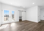 Thumbnail 6 of 27 - A room with white walls and wooden flooring, with a view of a building outside through the windows.