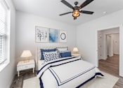 Thumbnail 3 of 27 - A bedroom with a bed, two lamps, and a ceiling fan.