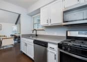 Thumbnail 30 of 40 - apartment property resident club house community kitchen with white cabinets and stainless steel appliances