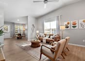 Thumbnail 2 of 9 - A living room with a brown rug, a wooden coffee table, and a fan on the ceiling.