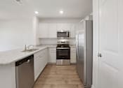 Thumbnail 1 of 19 - A kitchen with white cabinets and a stainless steel refrigerator.