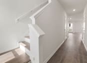Thumbnail 6 of 19 - A long hallway with a staircase on the left side.