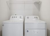 Thumbnail 13 of 19 - Two white washing machines in a small laundry room.