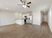 Thumbnail 3 of 19 - A spacious room with a ceiling fan and wooden flooring.